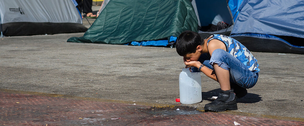 Migrant child drinking water. © Istock